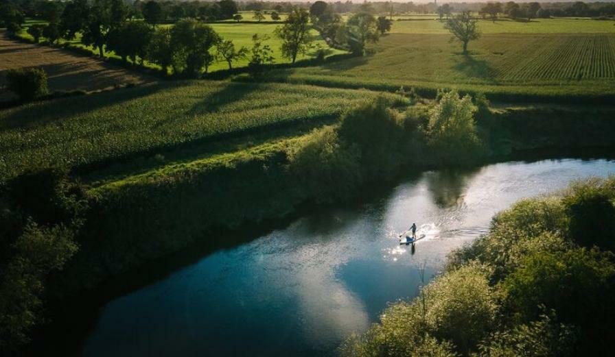 Drone image of person paddleboarding on the river