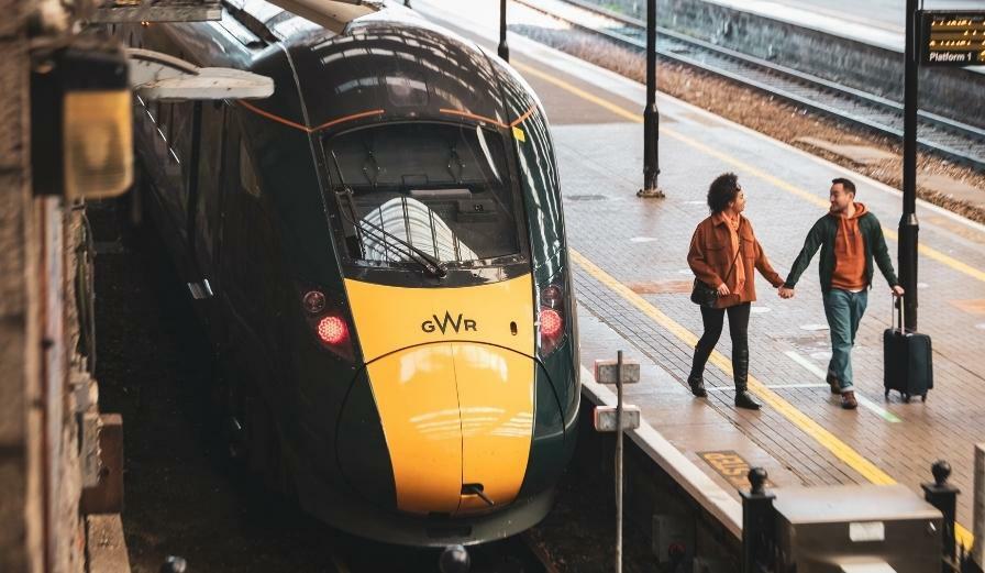 Photo of couple holding hands on train platform with GWR train stationary at station