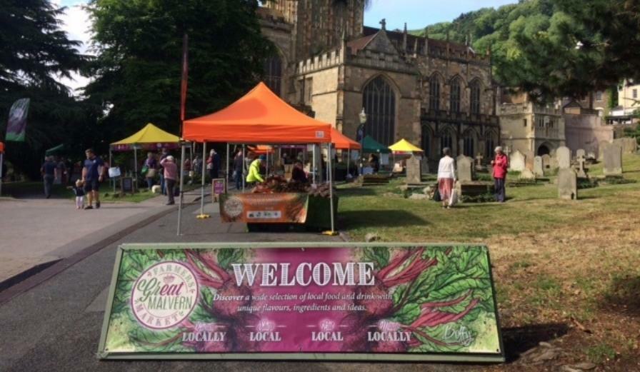 Photo of farmers market at Malvern with stall holders and church in the background