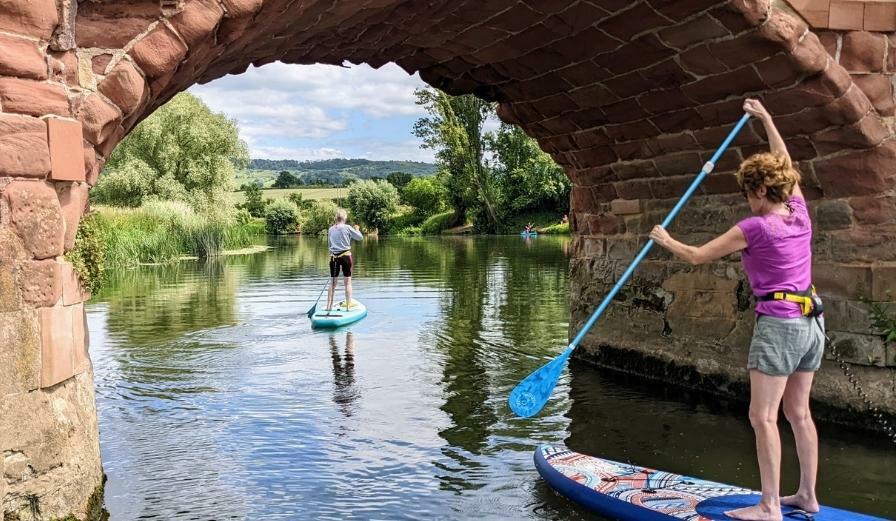 Photo of two people paddle boarding along the River Avon