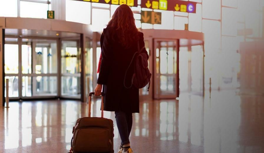 Photo of visitor leaving arrivals at Airport carrying a suitcase