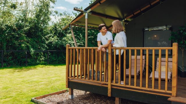Photo of a couple on a balcony of a Safari Tent