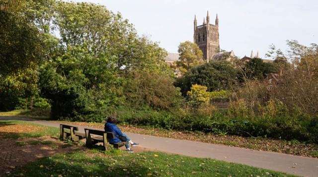 Photo of a person sitting on a bench looking towards Worcester Cathedral 1