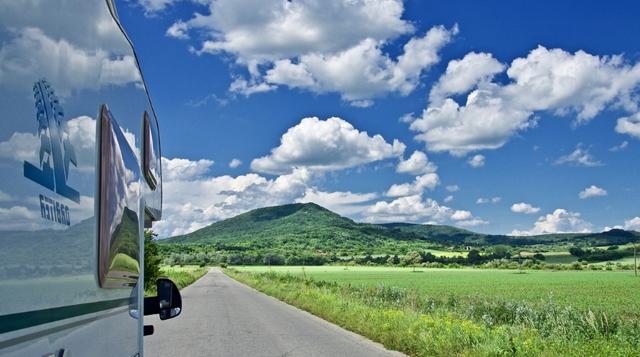 Photo of campervan on a road looking towards a hill