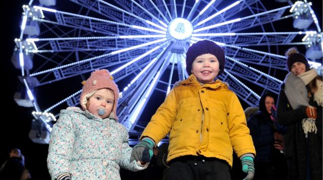 Photo of two children holding hands with Ferris wheel in the background