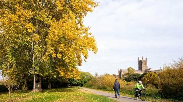 Photo of walker and cyclists along the River Severn with cathedral in the background