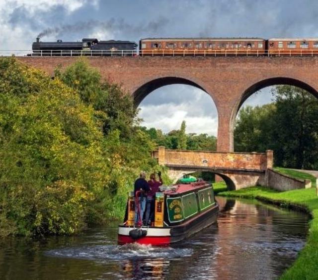 Photo of canal boats going through Kidderminster with steam train going over a bridge 1